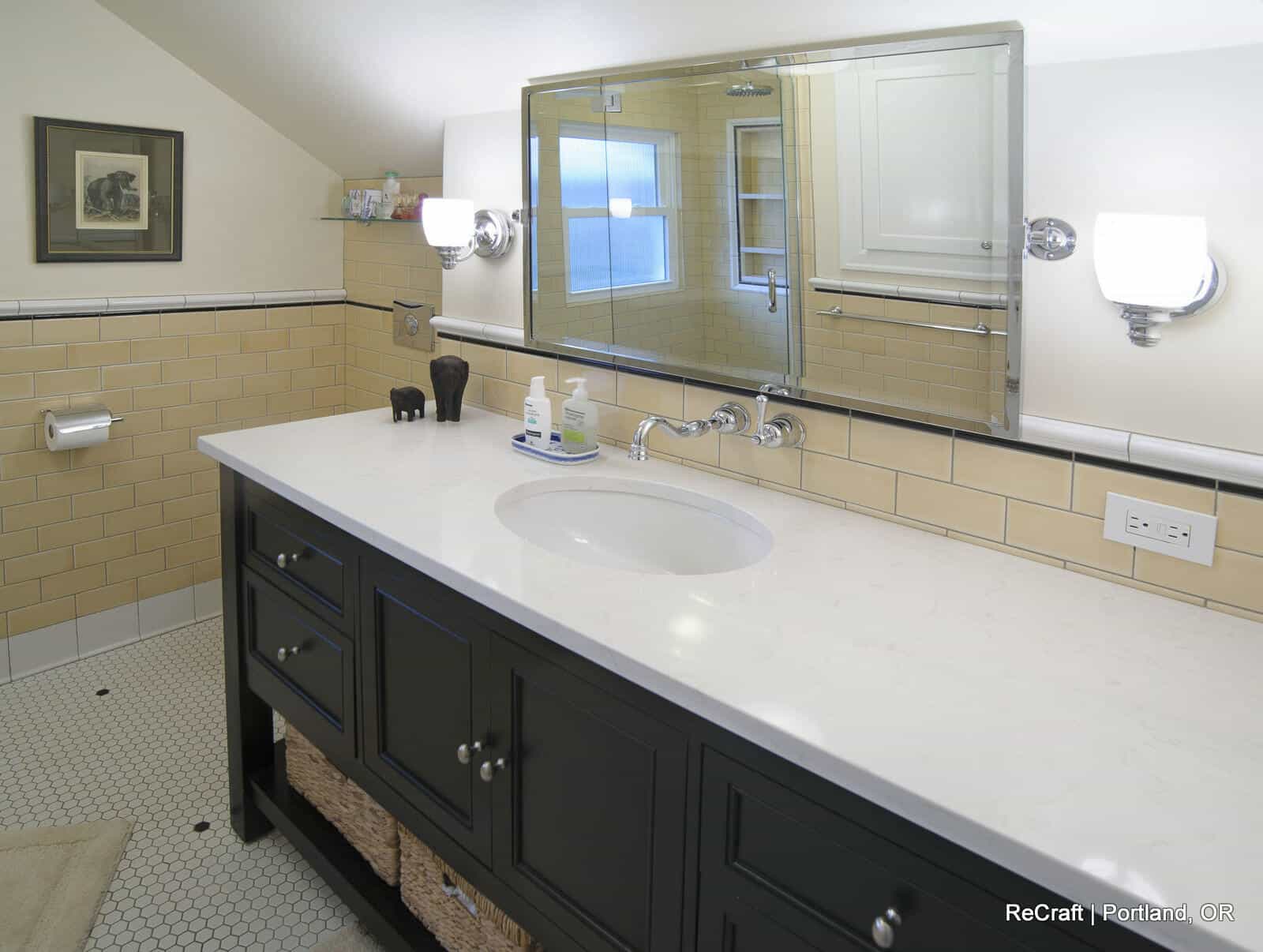 Modern bathroom vanity with black cabinetry, white countertop, large mirror, and stylish lighting, showcasing ReCraft Home Remodeling’s design capabilities for Portland homeowners.