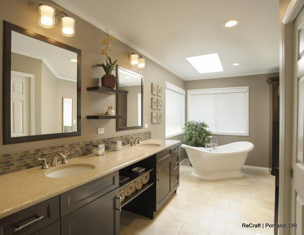 A modern bathroom with a double sink vanity, large mirrors, shelving, a freestanding bathtub, and a large window with blinds. There is a potted plant near the bathtub. Text reads "ReCraft | Portland, OR. A modern bathroom with a double sink vanity, large mirrors, shelving, a freestanding bathtub, and a large window with blinds. There is a potted plant near the bathtub. Text reads "ReCraft | Portland, OR.
