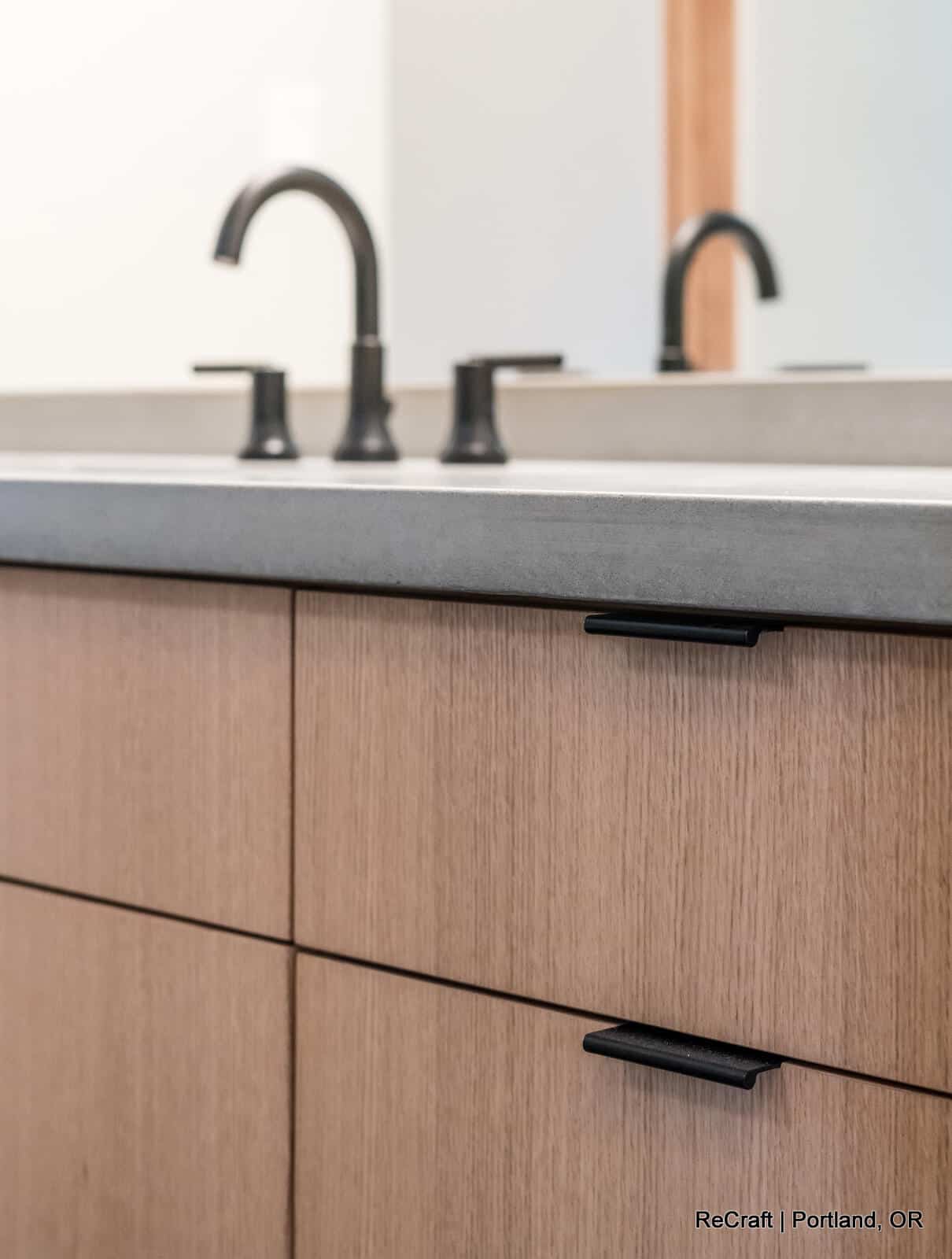 mcconnell - bathroom_sink Modern bathroom sink with sleek black faucets and wooden cabinetry, showcasing ReCraft Home Remodeling's design expertise in Portland.