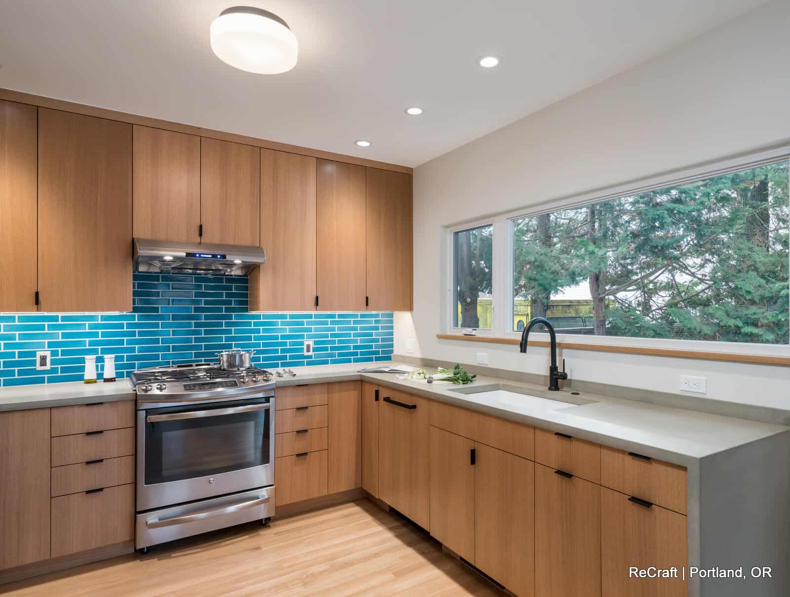 mcconnell - kitchen_side_view Modern kitchen featuring wooden cabinets, stainless steel appliances, turquoise backsplash, and a large window with natural light, showcasing ReCraft Home Remodeling's design expertise in Portland.
