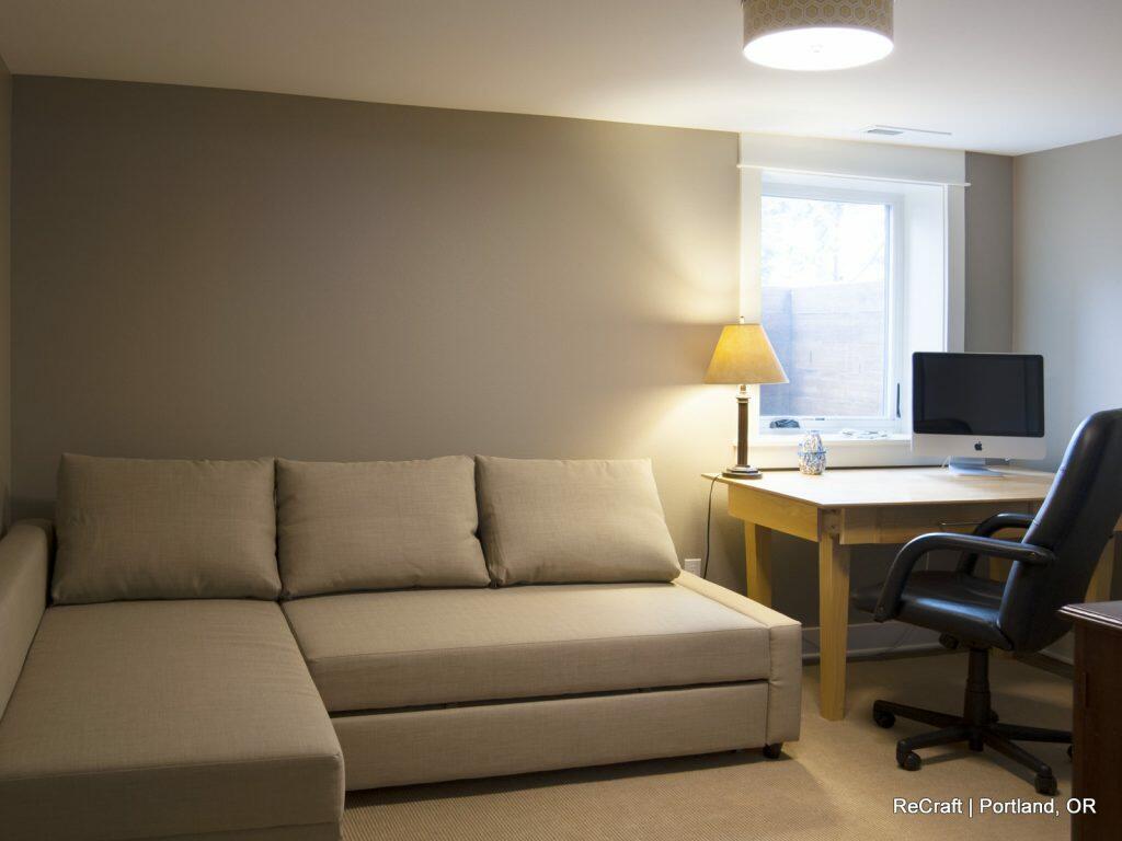 A home office features a beige sofa, a wooden desk with a computer, a table lamp, a leather office chair, and a window providing natural light. A home office features a beige sofa, a wooden desk with a computer, a table lamp, a leather office chair, and a window providing natural light.