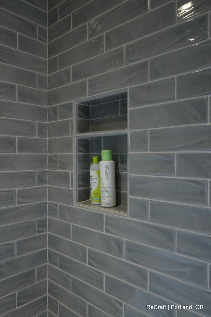Shower niche with two bottles of personal care products against glossy grey subway tiles. ReCraft | Portland, OR. Shower niche with two bottles of personal care products against glossy grey subway tiles. ReCraft | Portland, OR.