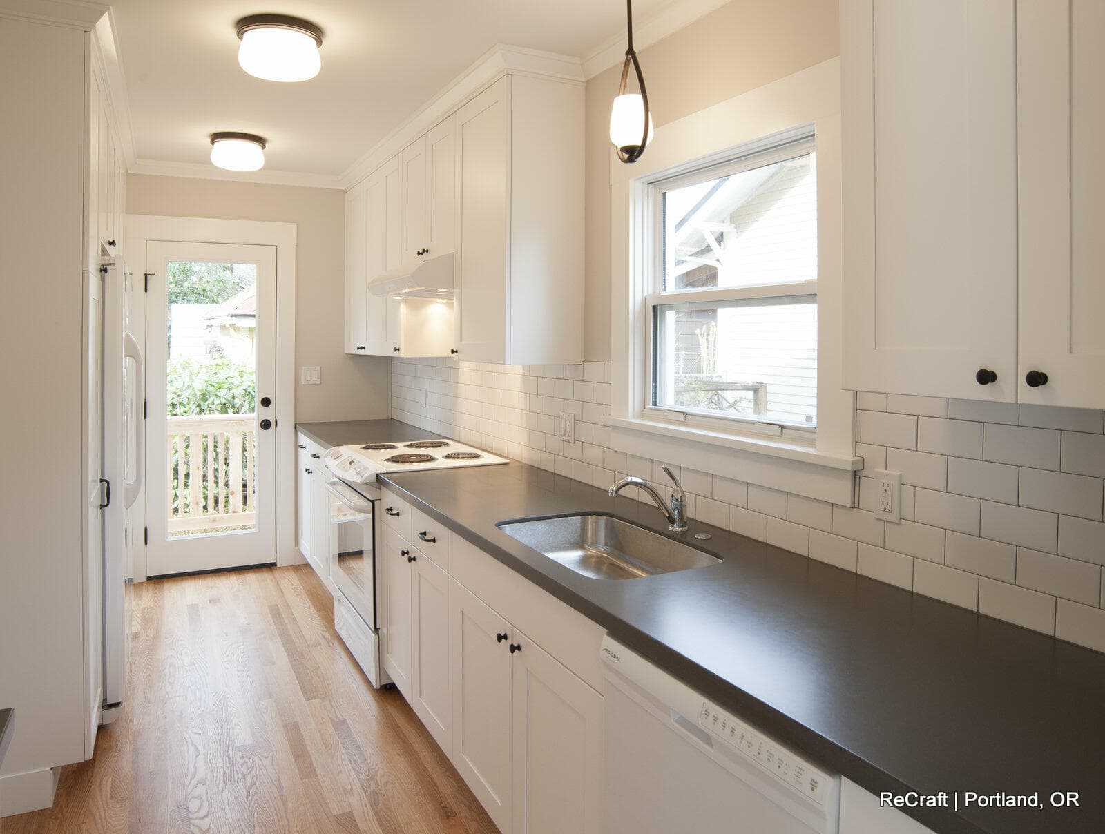 siddiqui-kitchen sink Modern kitchen design featuring white cabinetry, gray countertops, and subway tile backsplash, showcasing a remodeled space by ReCraft Home Remodeling in Portland, Oregon.