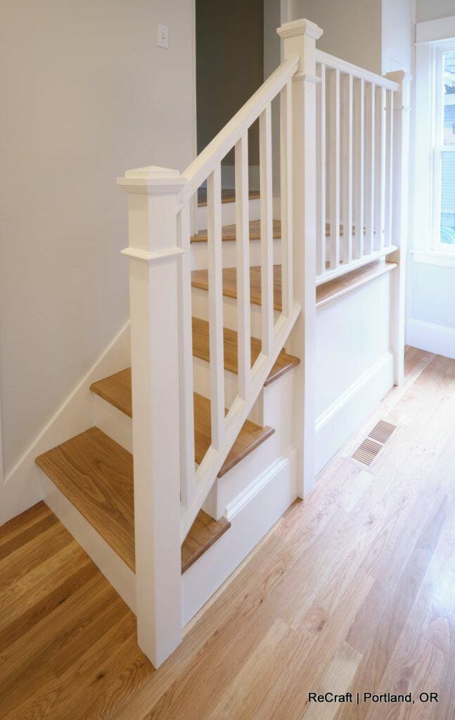 A wooden staircase with white railings and natural wood steps leads to an upper floor in a brightly lit room with wooden flooring. A wooden staircase with white railings and natural wood steps leads to an upper floor in a brightly lit room with wooden flooring.