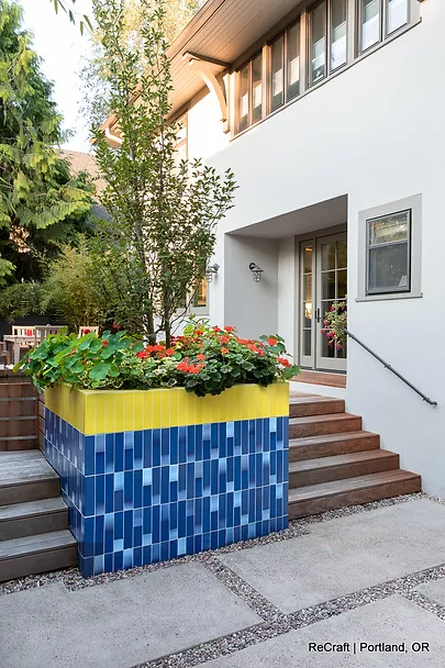 Colorful planter box with flowers, blue tiled design, and modern home entrance, showcasing ReCraft Home Remodeling's creative landscaping in Portland.