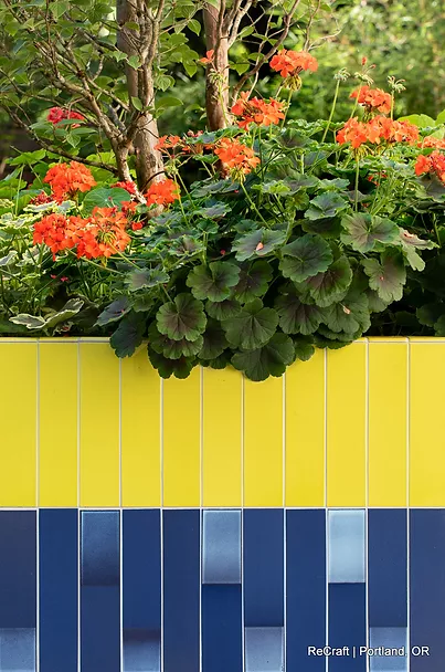 Colorful garden planter with vibrant orange flowers and lush green foliage, showcasing modern design elements relevant to home remodeling by ReCraft Home Remodeling in Portland.