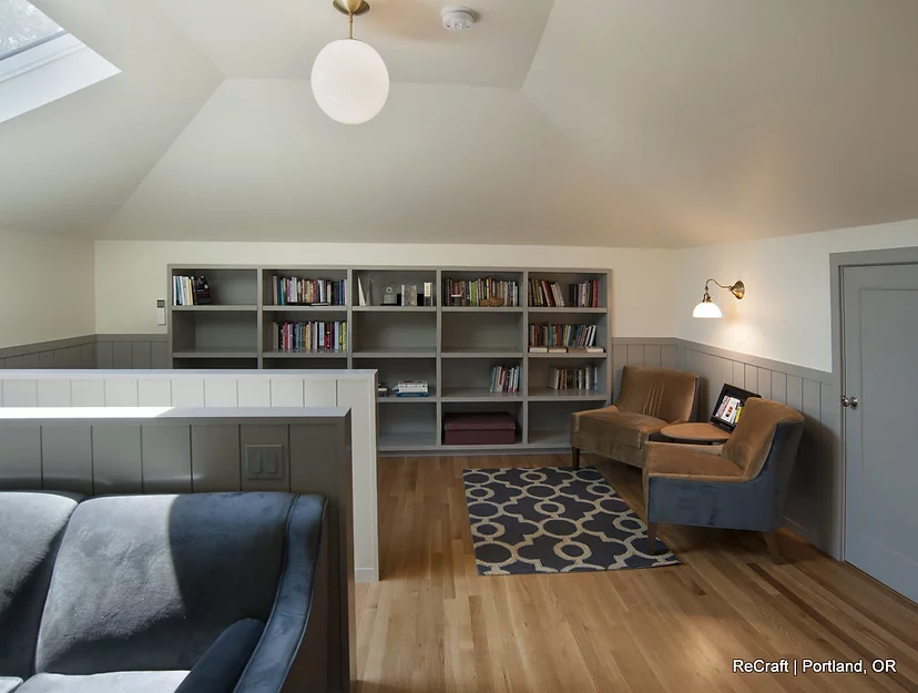 Cozy remodeled office space featuring built-in bookshelves, a comfortable seating area, and natural light from a skylight, showcasing ReCraft Home Remodeling's design capabilities in Portland.