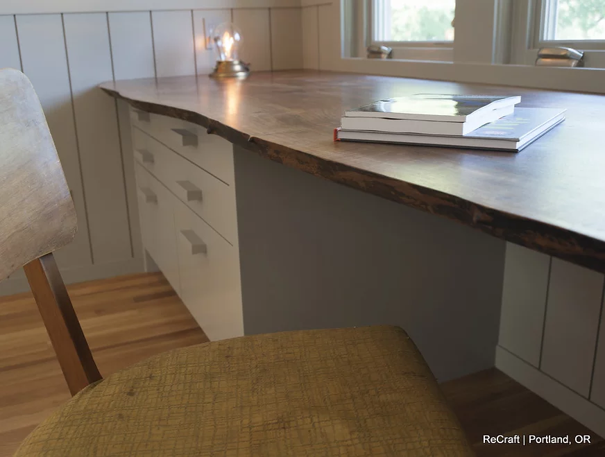 Modern home office desk with natural wood countertop, drawers, and a cozy chair, showcasing ReCraft Home Remodeling's design style in Portland, OR.