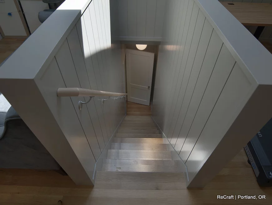 Staircase view with wooden steps and white paneling, showcasing ReCraft Home Remodeling's design aesthetic in Portland, OR.