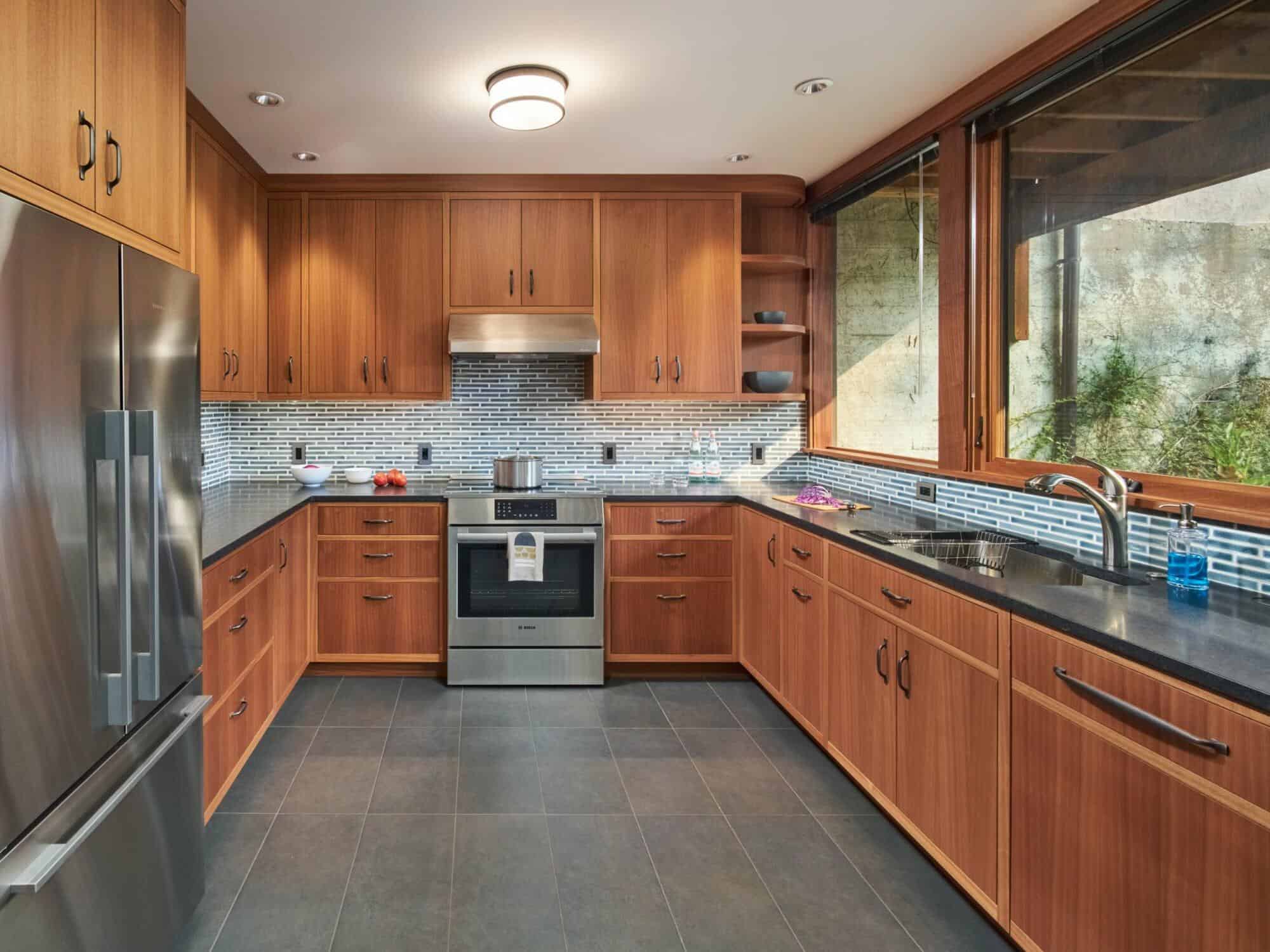 A modern U-shaped kitchen with wooden cabinets, stainless steel appliances, a tiled backsplash, and large windows providing natural light. A modern U-shaped kitchen with wooden cabinets, stainless steel appliances, a tiled backsplash, and large windows providing natural light.