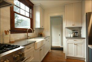 A modern kitchen with white cabinetry, stainless steel appliances, a farmhouse sink, and wooden flooring. A window above the sink allows natural light to enter the space. A modern kitchen with white cabinetry, stainless steel appliances, a farmhouse sink, and wooden flooring. A window above the sink allows natural light to enter the space.