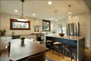 Modern kitchen with a wood dining table, island with marble countertop and stools, white cabinetry, stainless steel appliances, and pendant lights. Modern kitchen with a wood dining table, island with marble countertop and stools, white cabinetry, stainless steel appliances, and pendant lights.