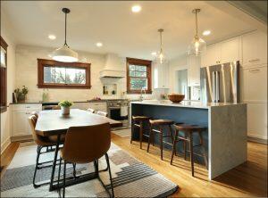 Modern kitchen with wooden floors, white cabinets, stainless steel appliances, a central island with bar stools, and a dining table with four chairs. Multiple pendant lights illuminate the space. Modern kitchen with wooden floors, white cabinets, stainless steel appliances, a central island with bar stools, and a dining table with four chairs. Multiple pendant lights illuminate the space.