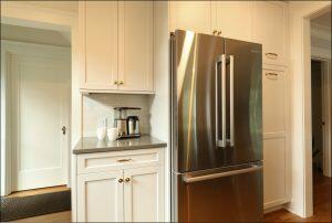 A modern kitchen featuring a stainless steel French door refrigerator, white cabinetry, a grey countertop with a coffee maker and two mugs. The room is well-lit with natural light. A modern kitchen featuring a stainless steel French door refrigerator, white cabinetry, a grey countertop with a coffee maker and two mugs. The room is well-lit with natural light.
