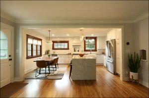 A modern kitchen with white cabinets, a large island, stainless steel appliances, and a wooden dining table with four chairs located near windows. The space features wooden floors and pendant lighting. A modern kitchen with white cabinets, a large island, stainless steel appliances, and a wooden dining table with four chairs located near windows. The space features wooden floors and pendant lighting.