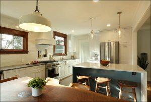 A modern kitchen with white cabinets, stainless steel appliances, a central island with wooden stools, pendant lights, and a dining table with a potted plant. A modern kitchen with white cabinets, stainless steel appliances, a central island with wooden stools, pendant lights, and a dining table with a potted plant.