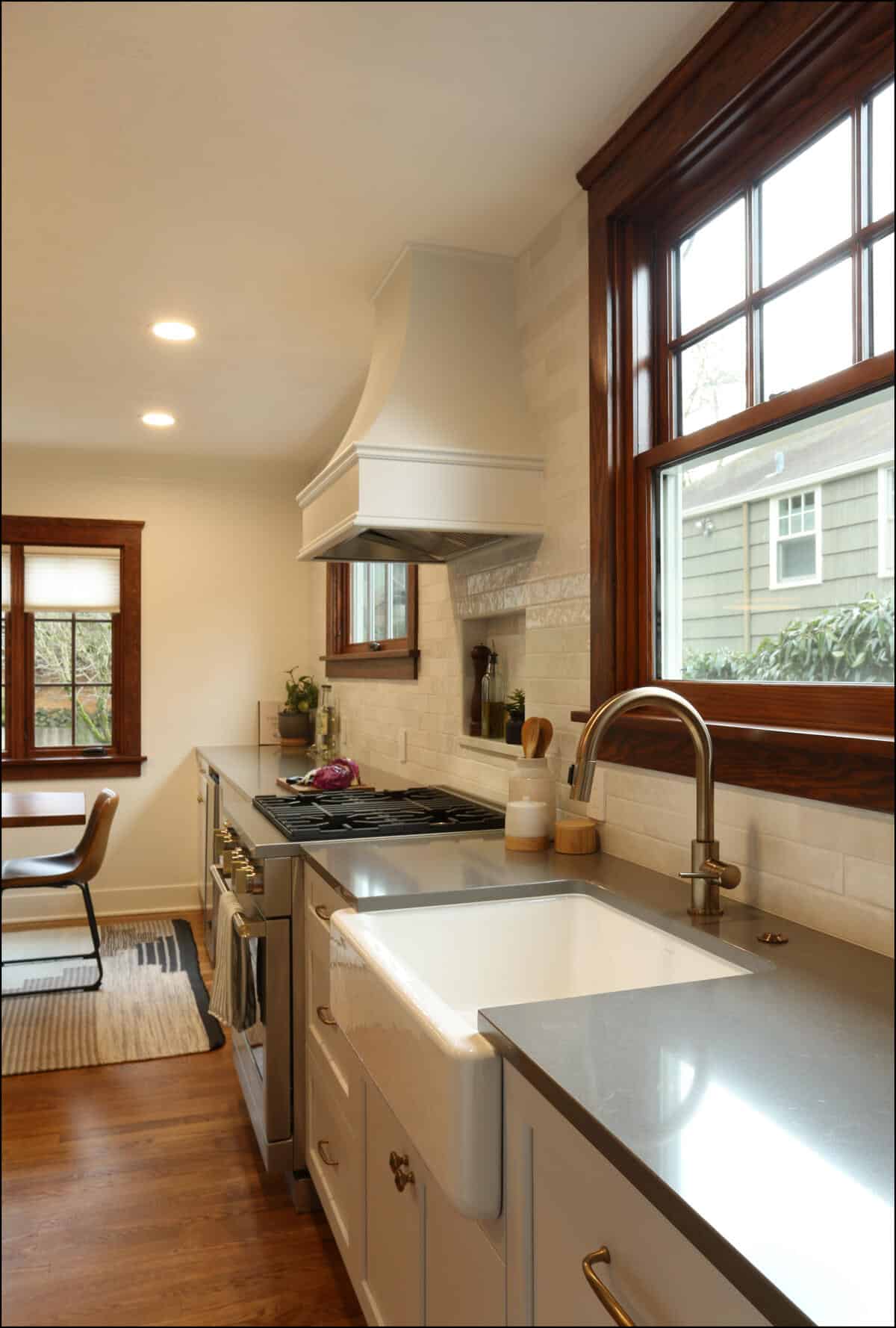 A modern kitchen featuring a farmhouse sink, stainless steel appliances, a gas stove with a range hood, ample counter space, and a large window providing natural light. A modern kitchen featuring a farmhouse sink, stainless steel appliances, a gas stove with a range hood, ample counter space, and a large window providing natural light.