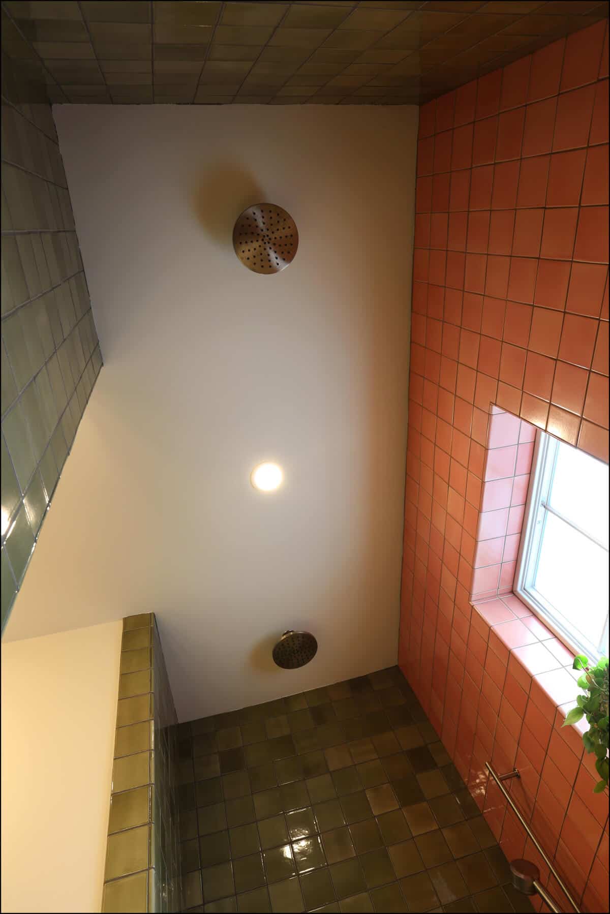 Bathroom interior featuring modern lighting fixtures, textured green and orange tile walls, and a window, showcasing ReCraft Home Remodeling's design aesthetics in Portland.