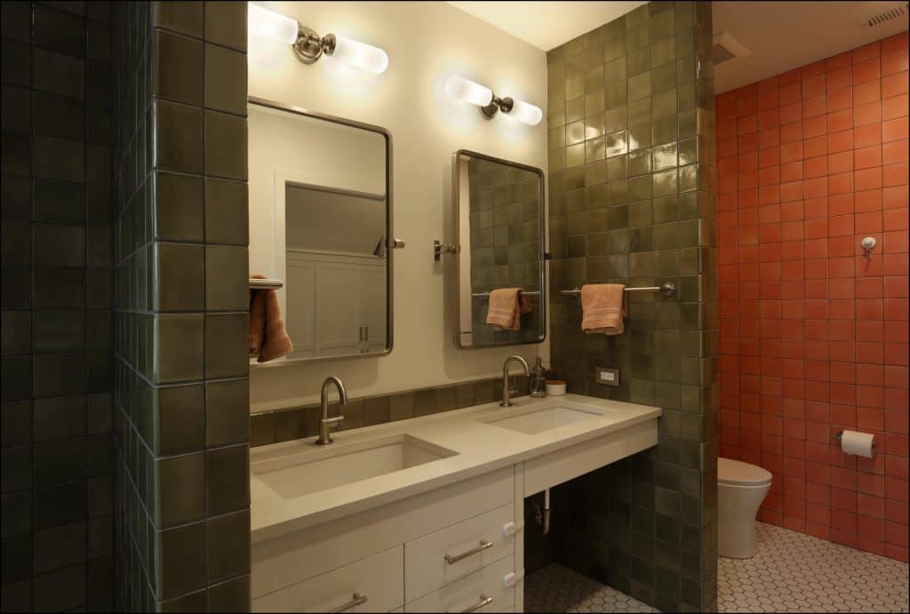 Bathroom with two sinks, green and red tiled walls, mirrors, and a toilet. Bathroom with two sinks, green and red tiled walls, mirrors, and a toilet.