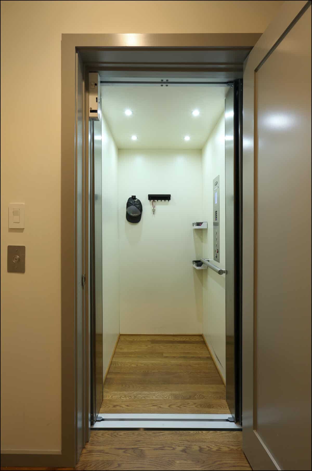 An empty modern elevator with wooden flooring, open doors, and interior lighting. Elevator interior with wooden flooring and modern lighting, showcasing a clean and spacious design, relevant to whole house remodeling projects by ReCraft Home Remodeling in Portland, Oregon.