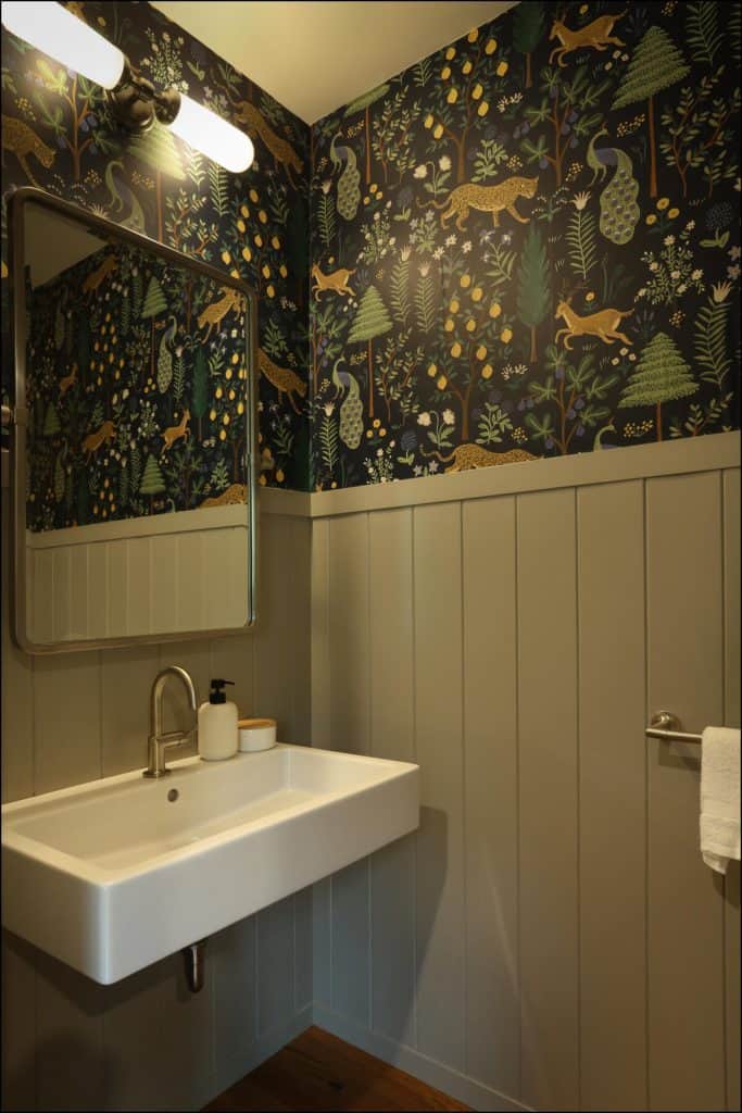 Small bathroom with a wall-mounted sink, decorative wallpaper with forest animals, and a rectangular mirror. Small bathroom with a wall-mounted sink, decorative wallpaper with forest animals, and a rectangular mirror.