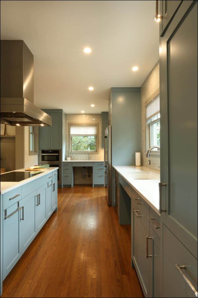 Modern kitchen with blue cabinets, hardwood flooring, and stainless steel appliances. Large window above the counter provides natural light. Modern kitchen with blue cabinets, hardwood flooring, and stainless steel appliances. Large window above the counter provides natural light.