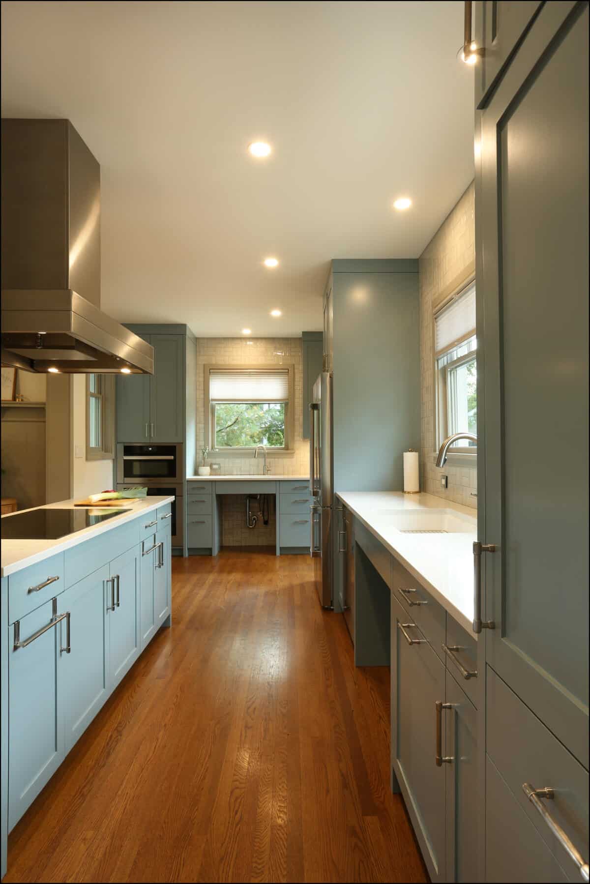 Modern kitchen with blue cabinets, hardwood flooring, and stainless steel appliances. Large window above the counter provides natural light. Modern kitchen with blue cabinets, hardwood flooring, and stainless steel appliances. Large window above the counter provides natural light.