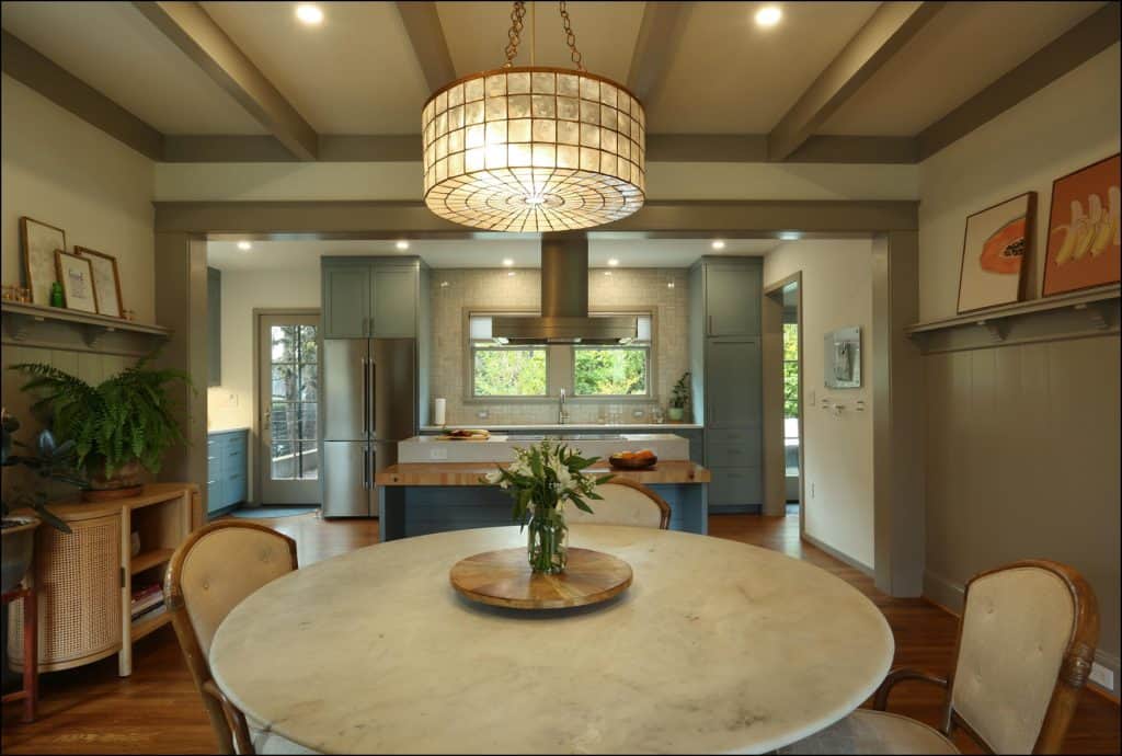 Spacious kitchen with a round marble dining table, beige chairs, a large ceiling light, and blue cabinets. The room features wood flooring and modern decor. Spacious kitchen with a round marble dining table, beige chairs, a large ceiling light, and blue cabinets. The room features wood flooring and modern decor.