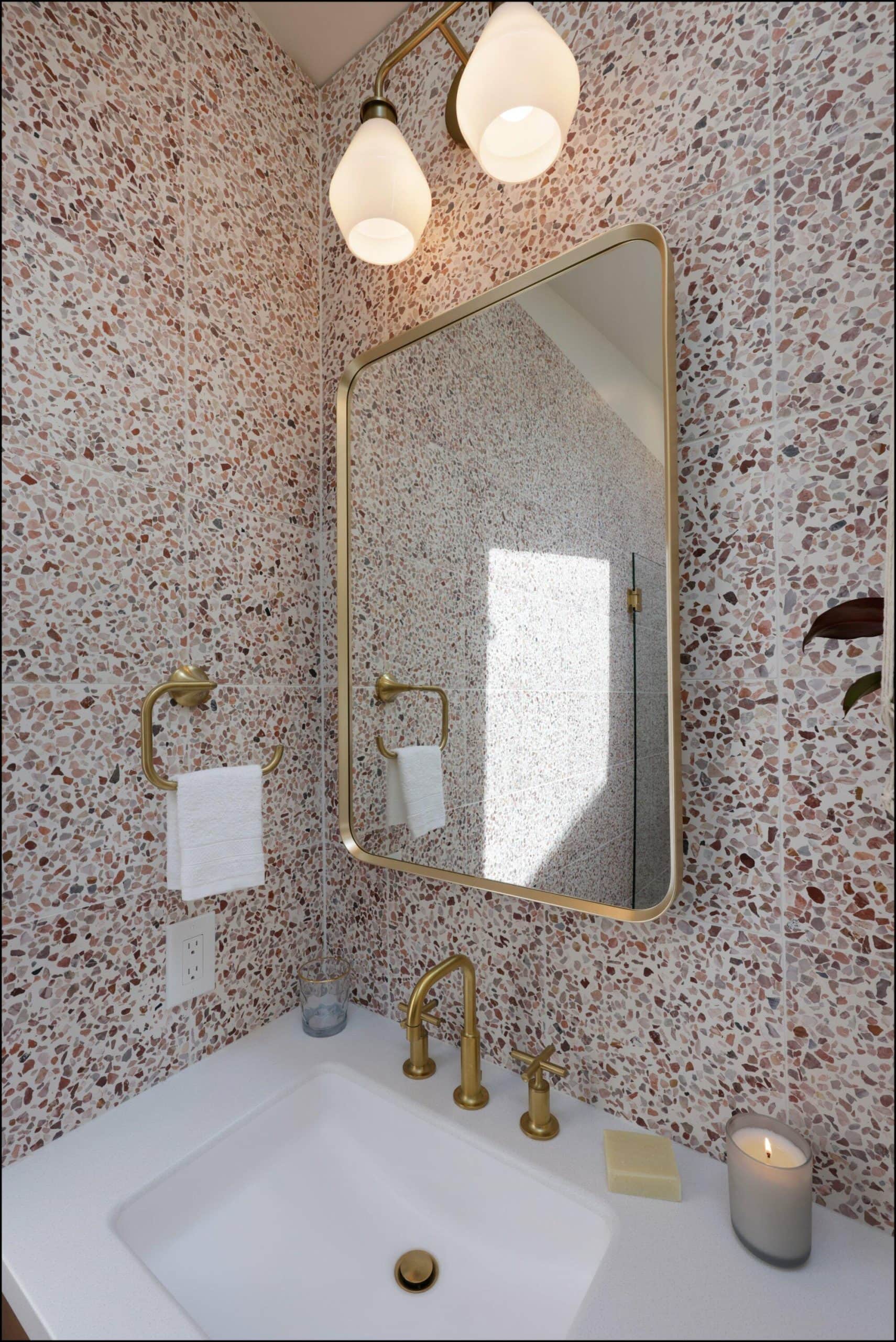 Bathroom faucet and mirror detail featuring gold fixtures, white sink, and textured wall in a remodeled Portland bathroom.