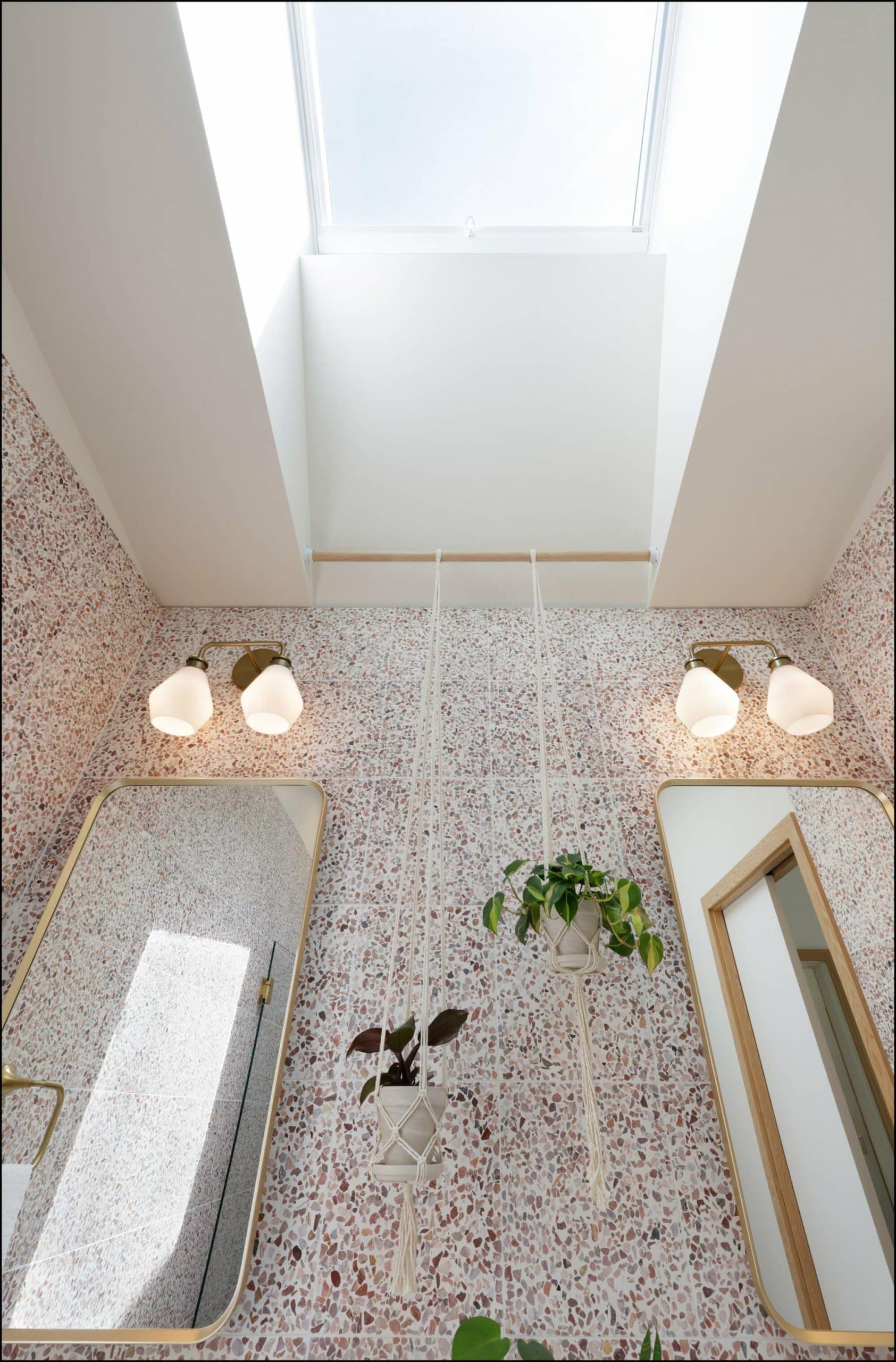 Bathroom interior featuring a skylight, wall-mounted mirrors, and a hanging plant, showcasing modern design elements and natural light in a Portland bathroom remodel by ReCraft Home Remodeling.