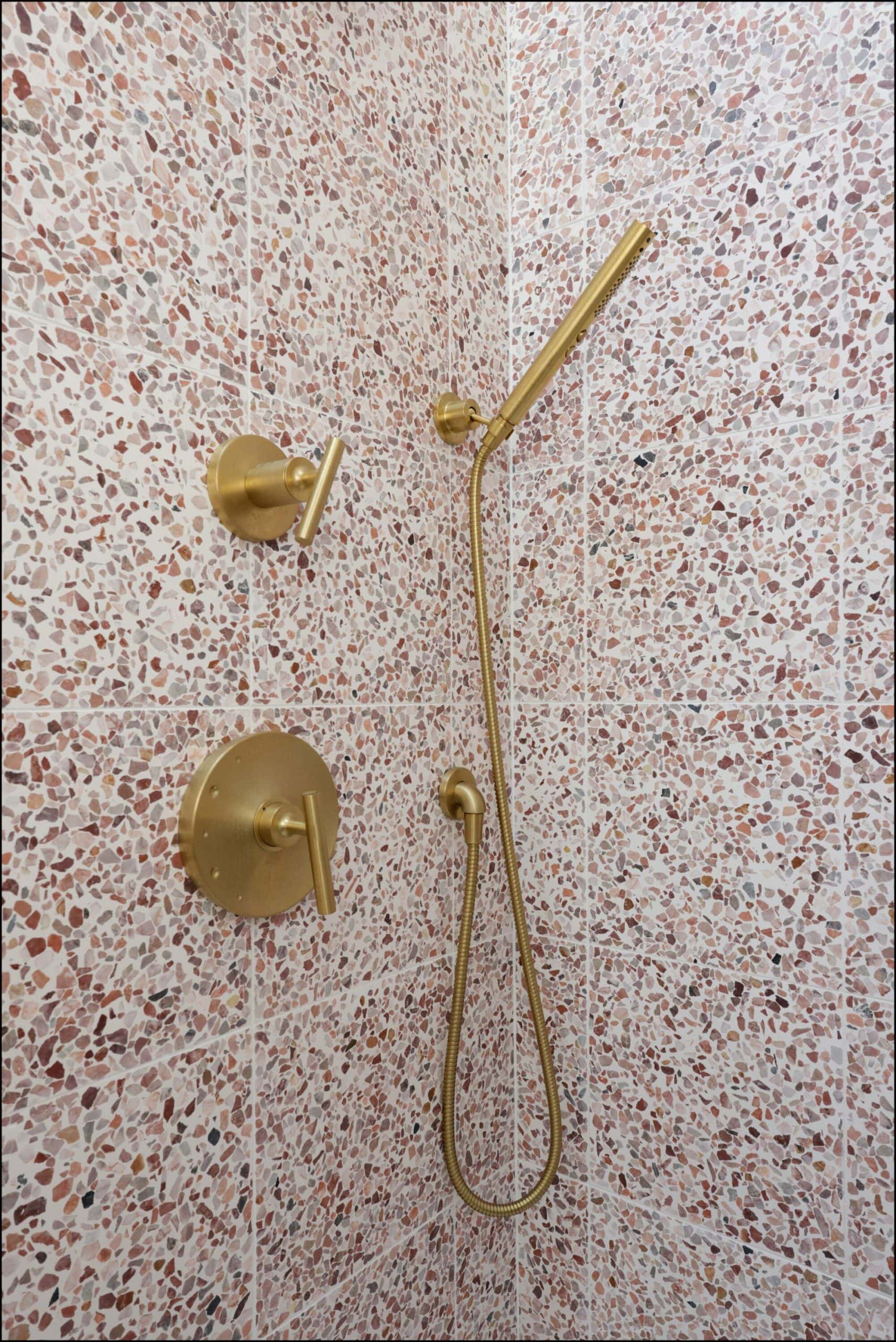 Handheld showerhead and faucet fixtures in a modern bathroom with textured pink tile walls, showcasing ReCraft Home Remodeling's elegant design in Portland bathroom renovations.