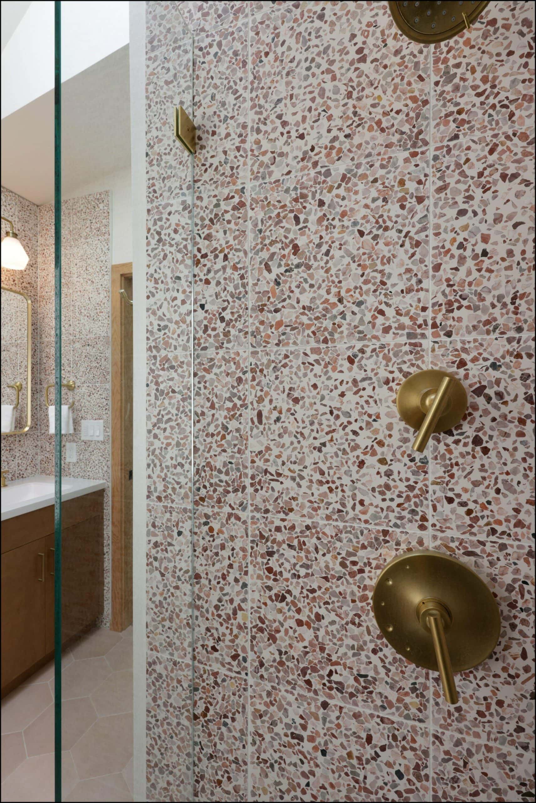 Bathroom shower hardware detail featuring textured pink terrazzo wall, gold fixtures, and modern design elements, showcasing ReCraft Home Remodeling's craftsmanship in Portland bathroom renovations.