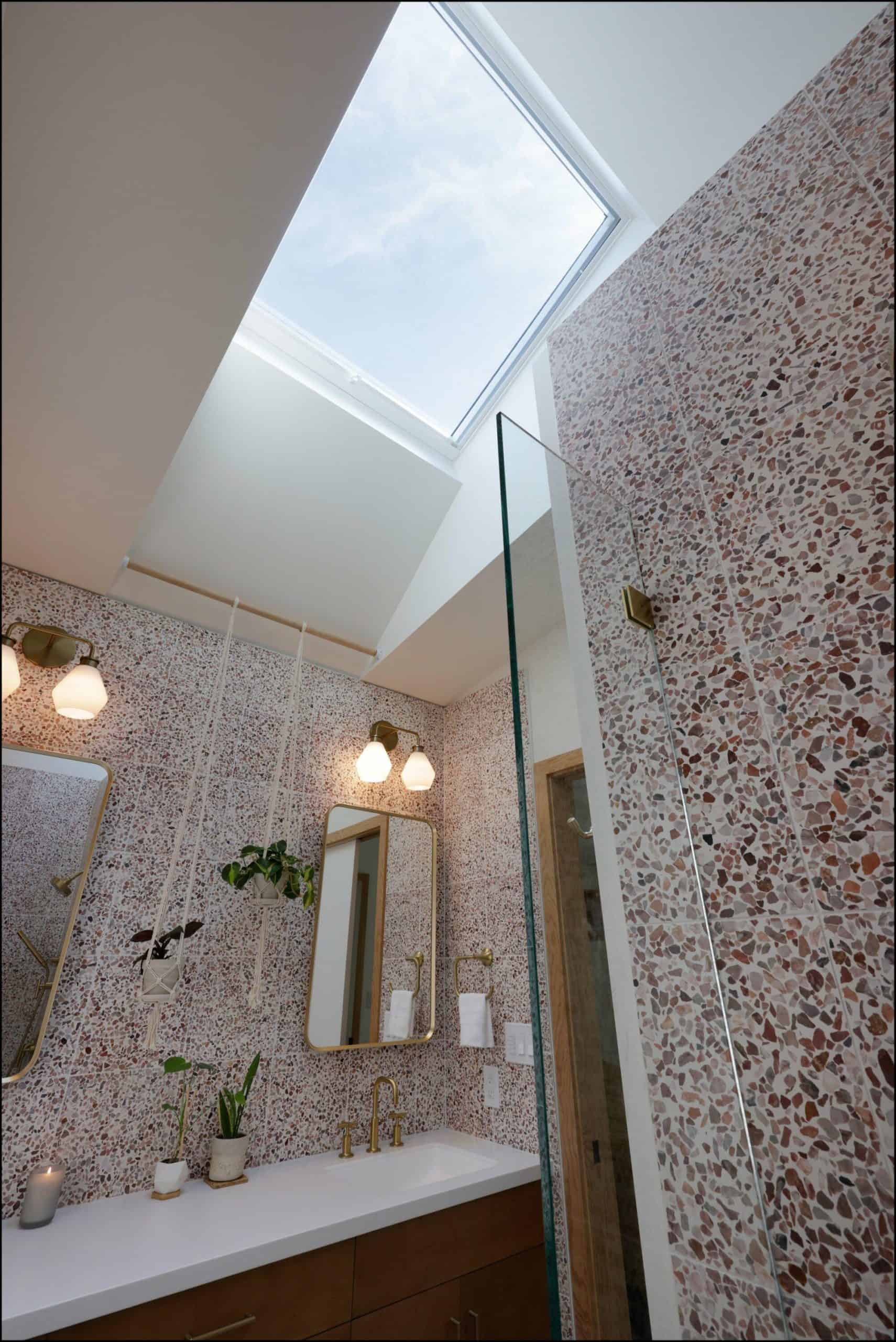 Modern bathroom interior featuring a skylight above a stylish vanity, terrazzo wall design, and pendant lighting, showcasing ReCraft Home Remodeling's design expertise in Portland.