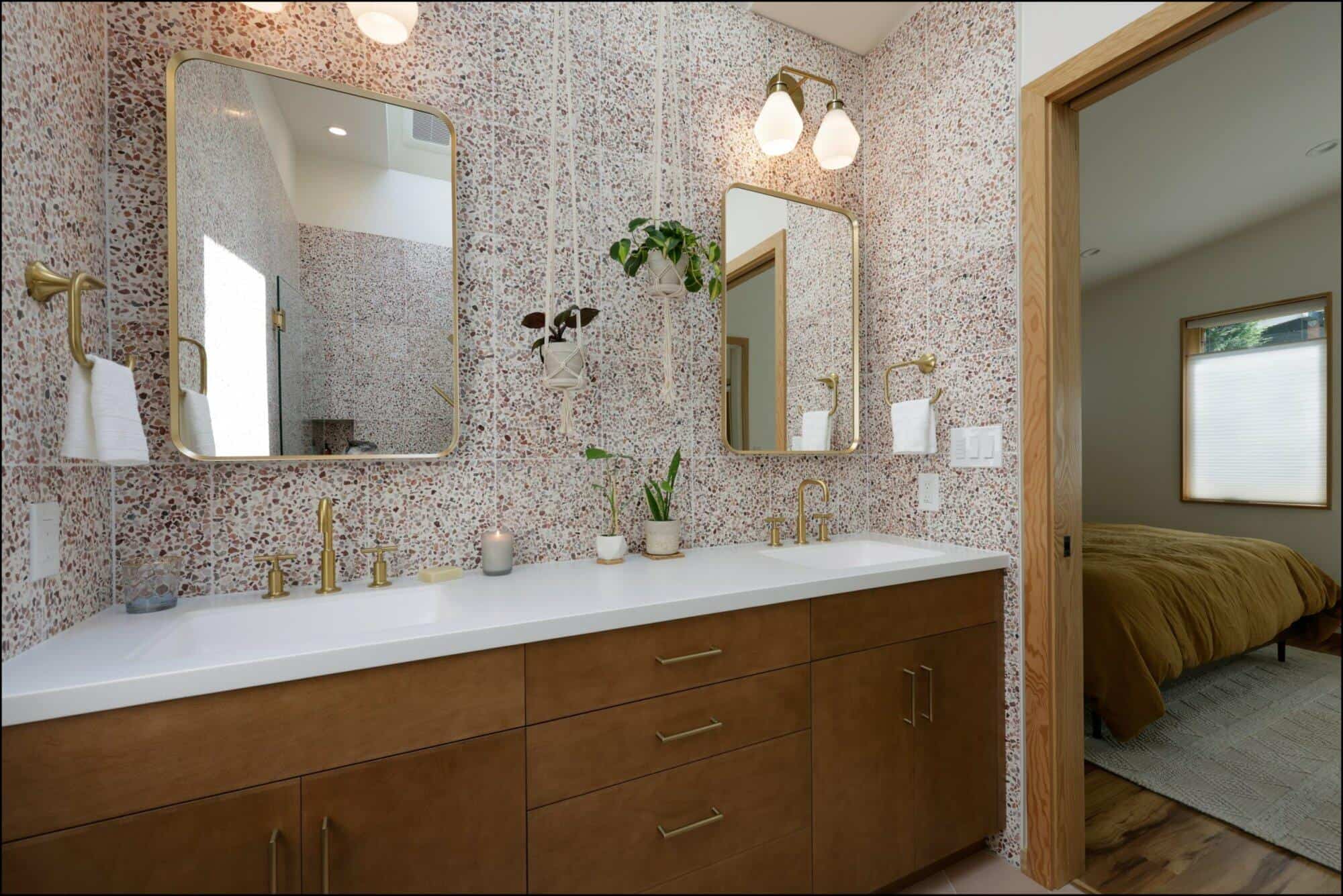Modern bathroom vanity with dual mirrors, gold fixtures, and textured wall, leading to a cozy bedroom in Portland bathroom remodel by ReCraft Home Remodeling.