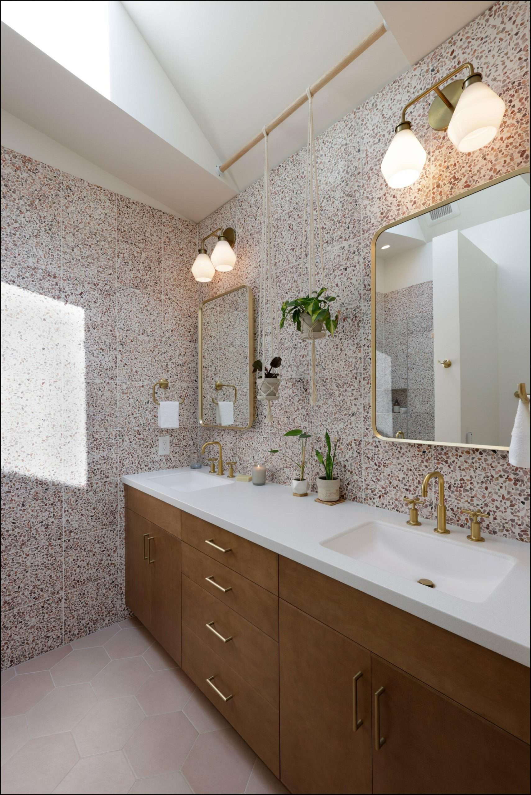 Modern bathroom vanity with double sinks, gold fixtures, large mirrors, and textured wall tiles, showcasing a stylish Portland bathroom remodel by ReCraft Home Remodeling.