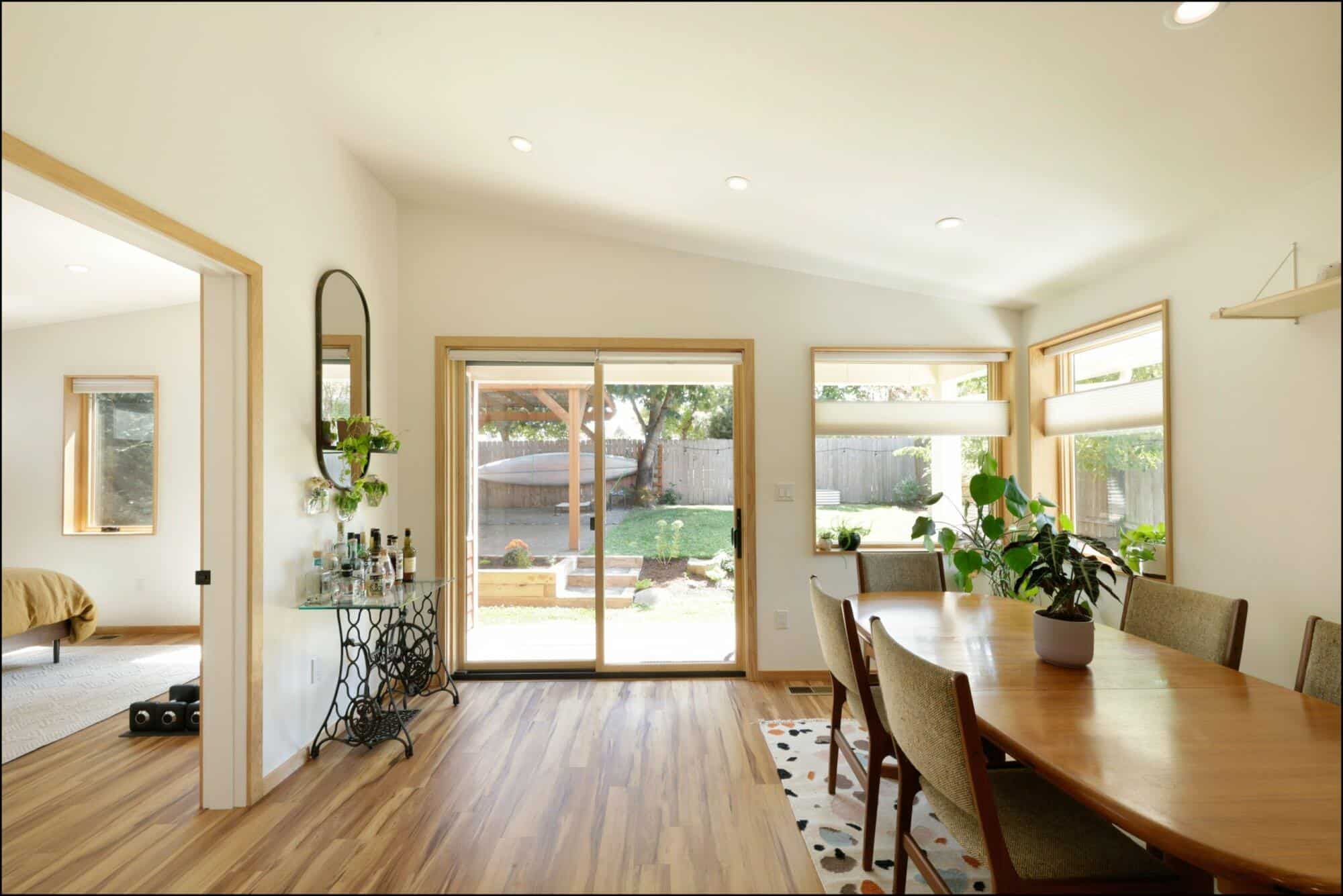 Dining room with wooden table, plants, and large back door leading to outdoor space, showcasing ReCraft's home remodeling design in Portland.