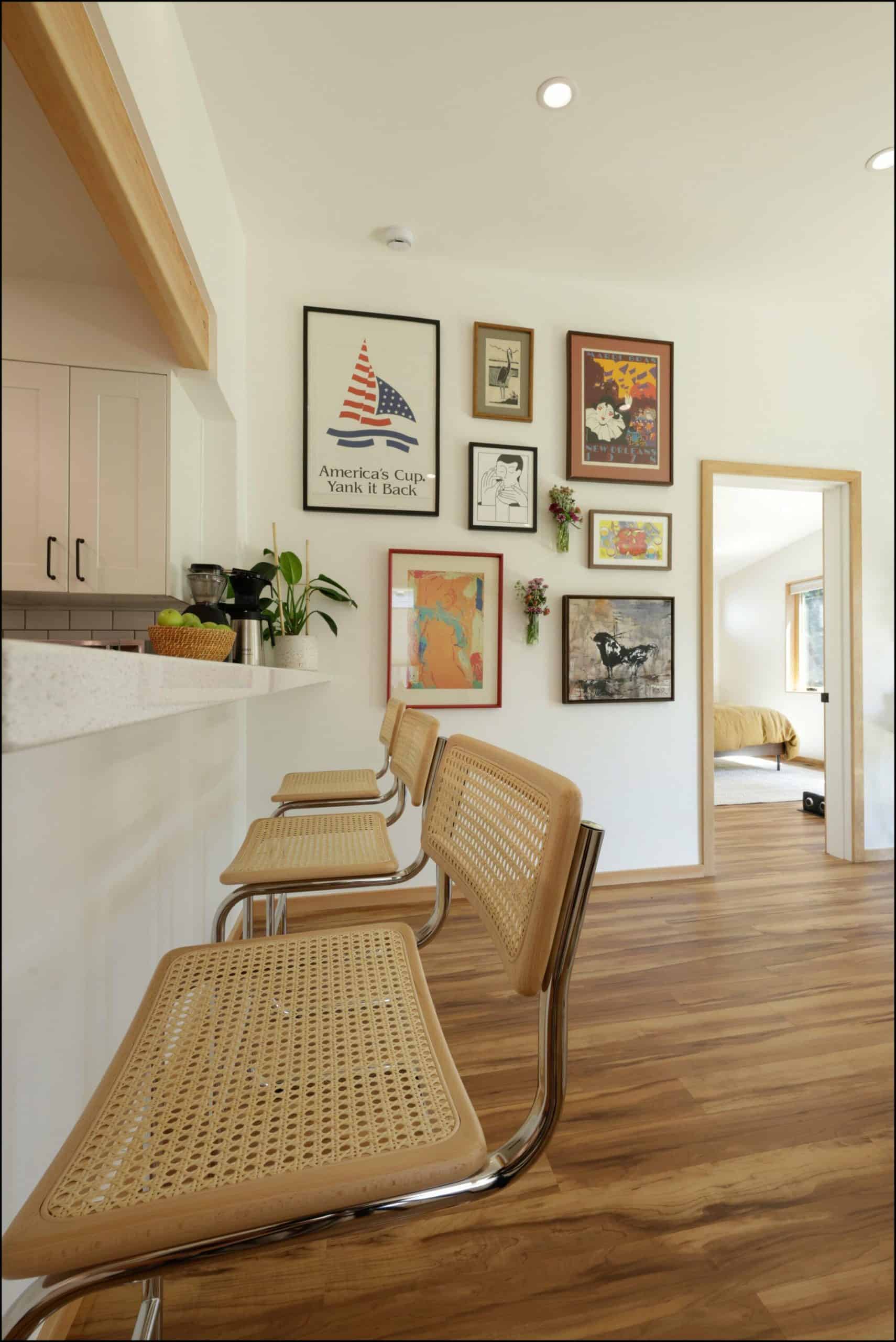 Dining area with modern bar chairs, gallery wall featuring framed artwork, and warm wood flooring, showcasing ReCraft Home Remodeling's design aesthetic in Portland.
