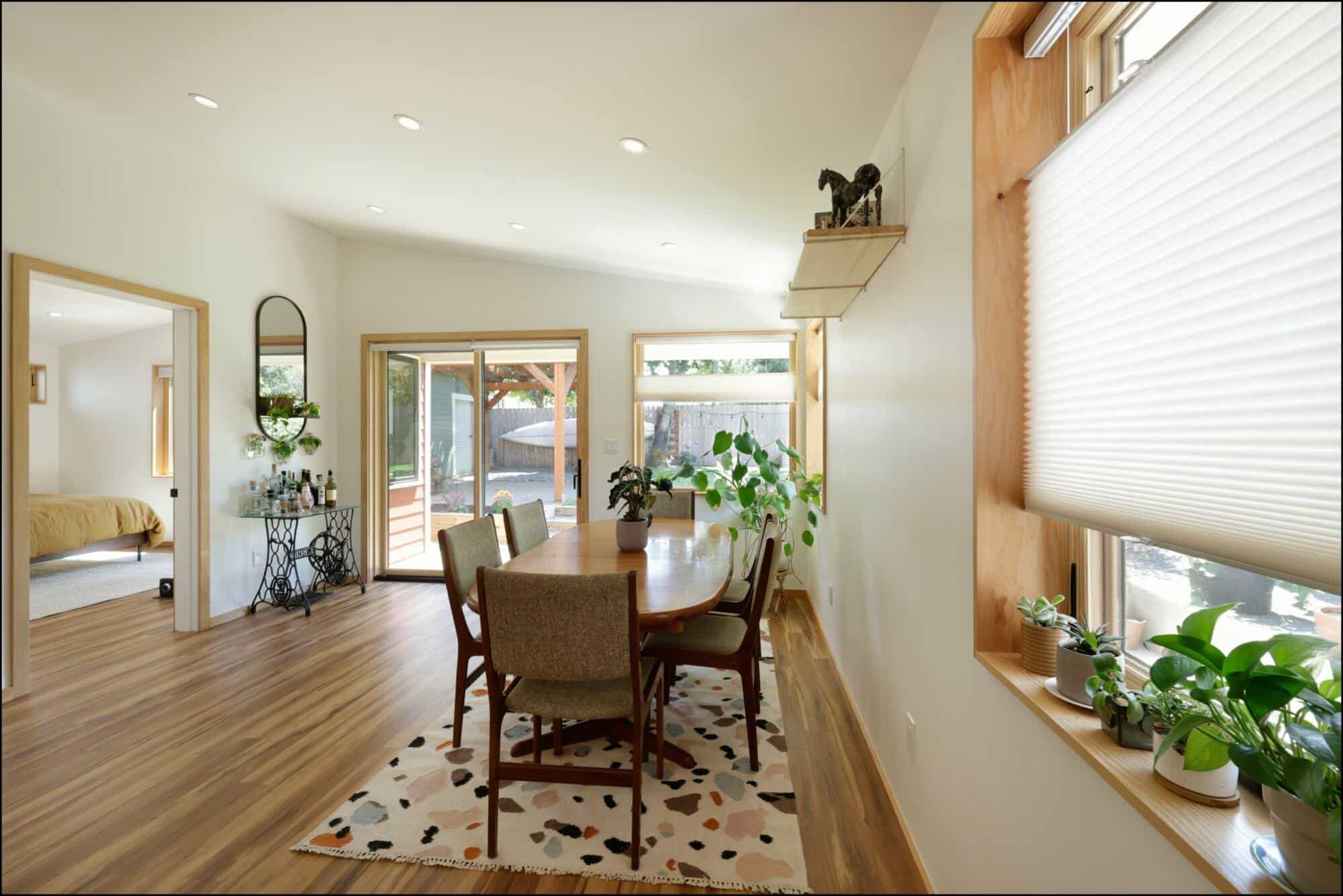 Modern dining room featuring a wooden dining table surrounded by chairs, large windows with natural light, and decorative plants, highlighting ReCraft Home Remodeling's interior design work in Portland.