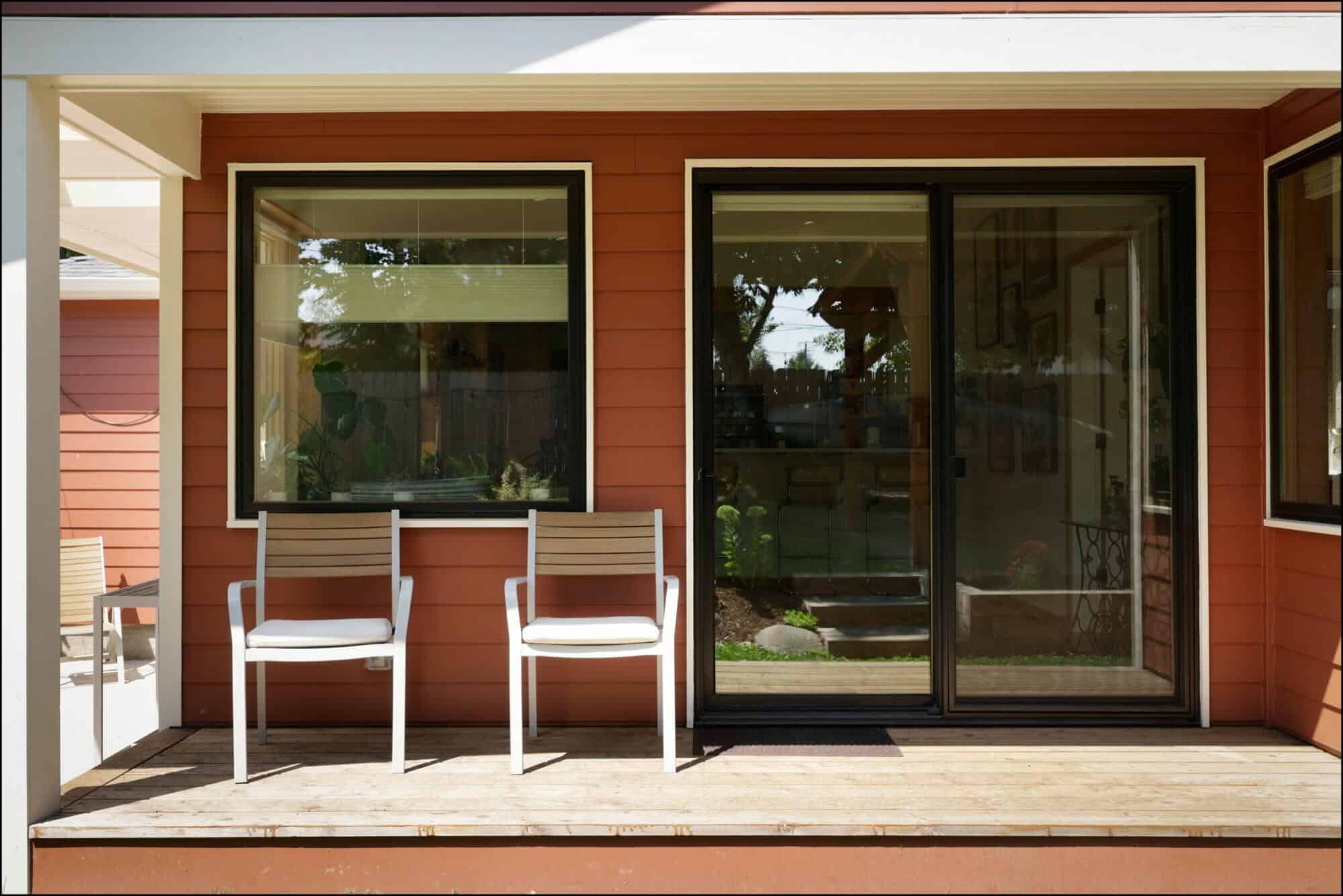 Exterior view of a remodeled back porch featuring two modern chairs, large sliding glass doors, and warm wood accents, showcasing ReCraft Home Remodeling's design capabilities in Portland.