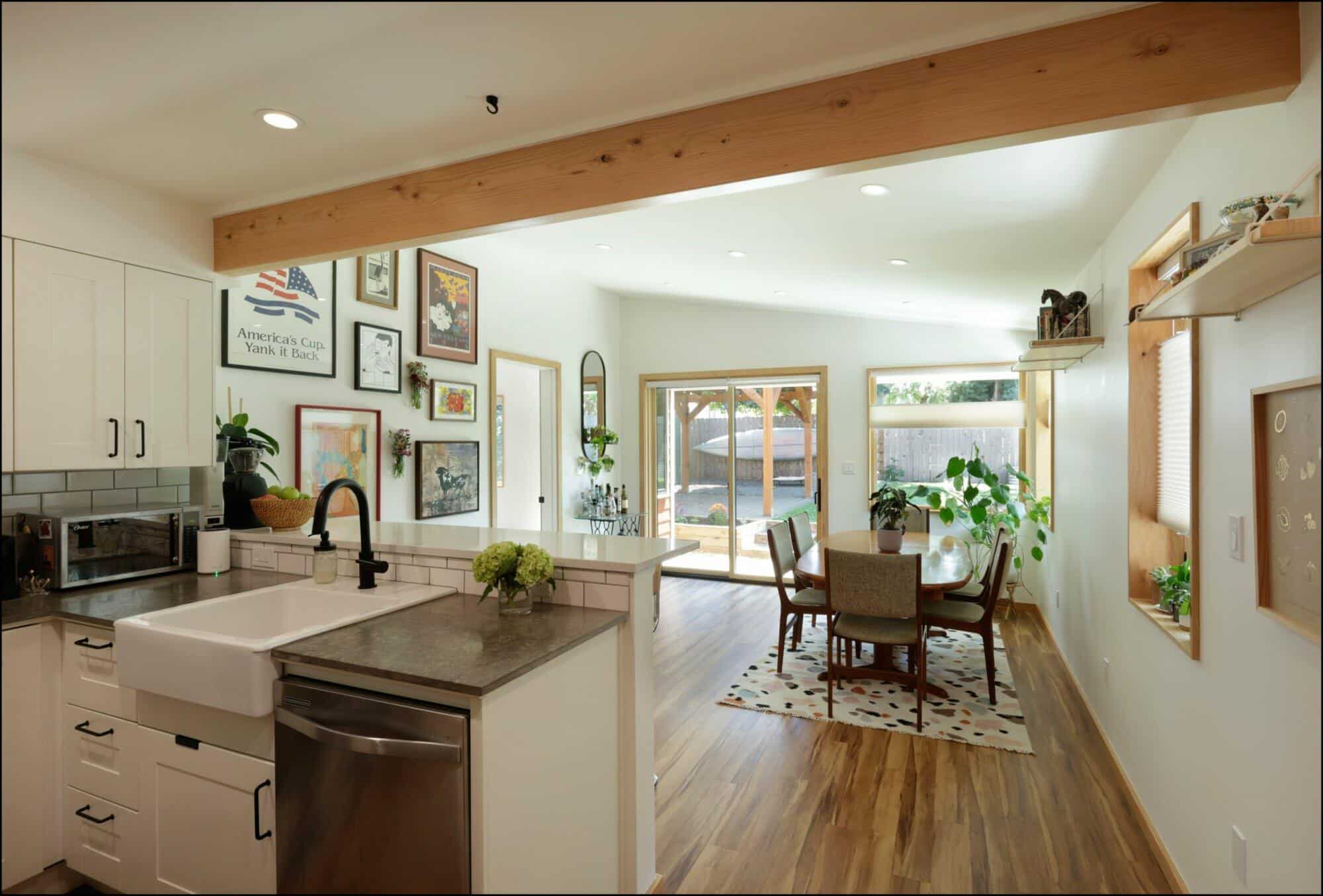Modern kitchen with farmhouse sink, cabinetry, and dining area featuring natural light and greenery, showcasing ReCraft Home Remodeling's design expertise in Portland.