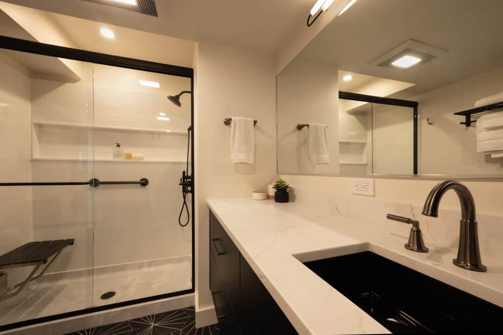 Modern bathroom featuring a glass shower enclosure, sleek black fixtures, and a dual sink vanity, showcasing ReCraft Home Remodeling's basement renovation work in Portland.