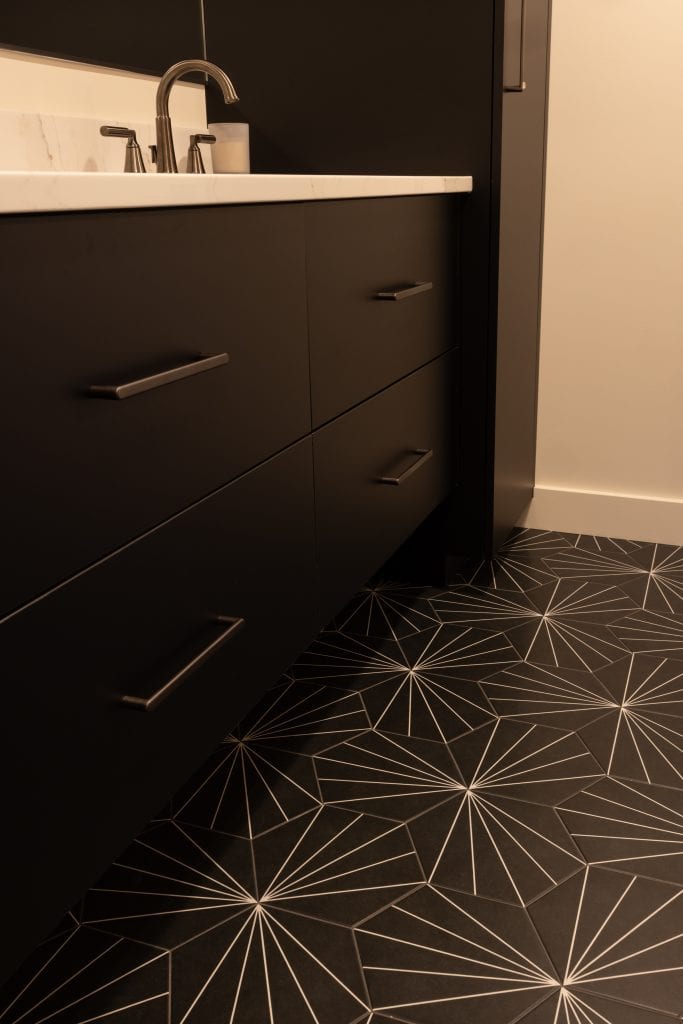 Modern bathroom interior featuring sleek black cabinetry and geometric patterned flooring, showcasing a stylish basement remodeling project by ReCraft Home Remodeling in Portland.