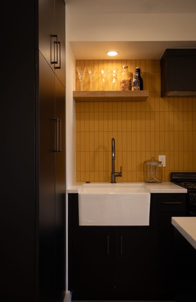 Modern basement kitchen with black cabinetry, farmhouse sink, and yellow backsplash, showcasing ReCraft Home Remodeling's design expertise in Portland.