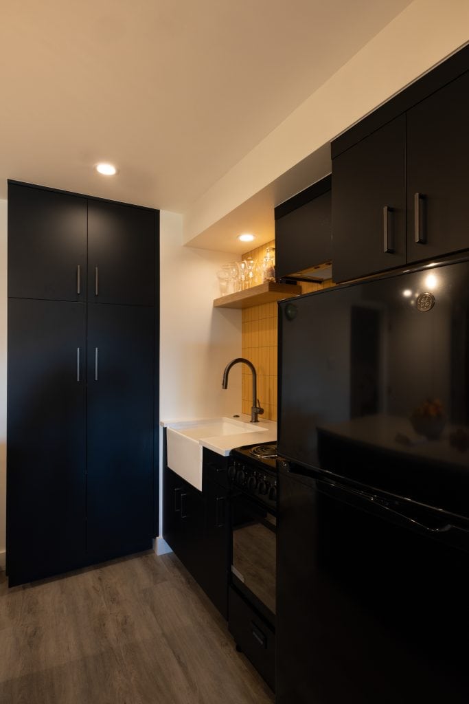Modern basement kitchen with black cabinetry, stainless steel appliances, and a white countertop, showcasing ReCraft Home Remodeling's design style in Portland.
