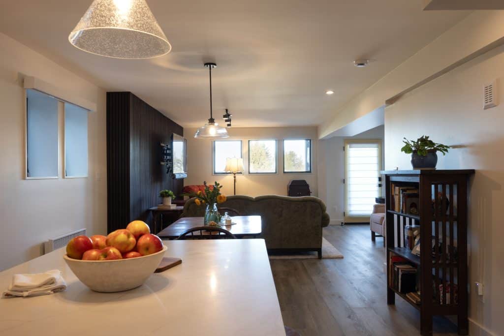 Modern basement renovation by ReCraft Home Remodeling featuring a bright, open living space with a dining area, decorative lighting, and a view of the cozy seating area.