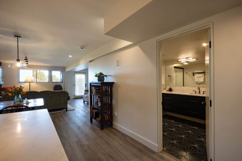 Basement remodeling project by ReCraft Home Remodeling, showcasing a modern living space with a view of a stylish bathroom and cozy seating area in Portland, Oregon.
