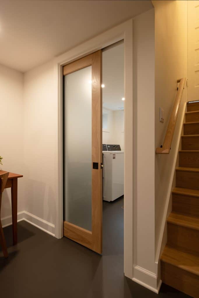 Basement entryway featuring a modern sliding glass door and wooden staircase, showcasing ReCraft Home Remodeling's design and renovation work in Portland.