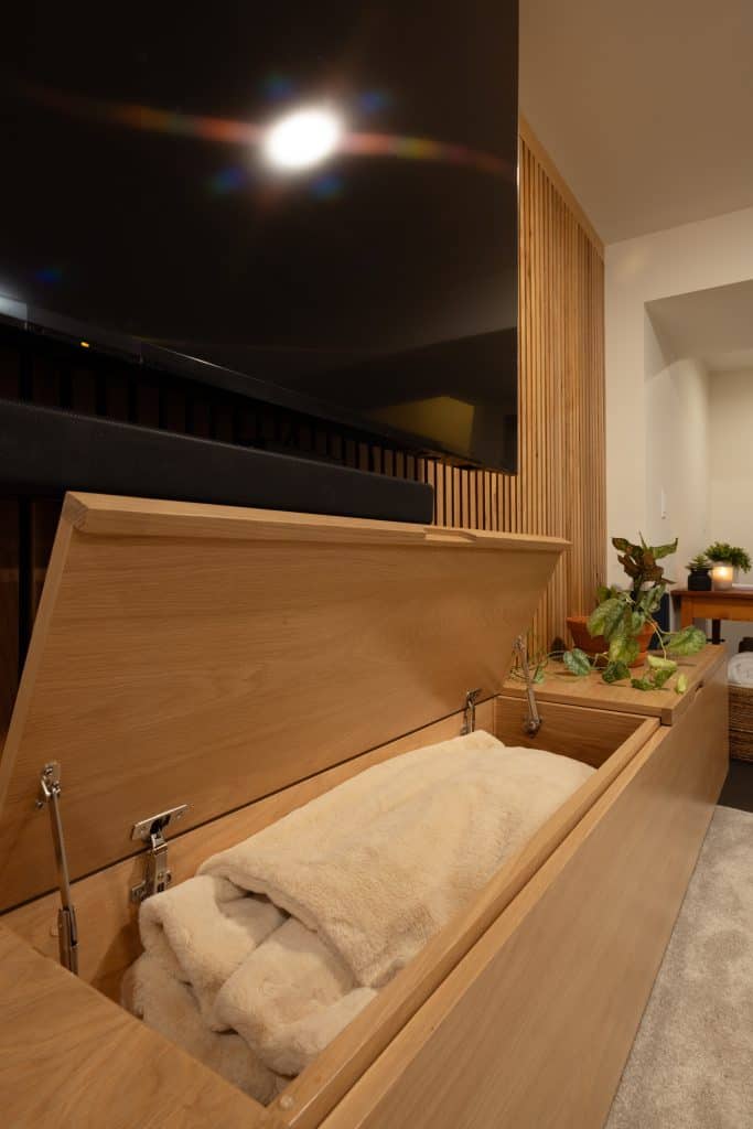 Modern basement storage solution featuring a wooden chest with a cozy blanket, designed for functionality and style in home remodeling projects by ReCraft Home Remodeling in Portland.