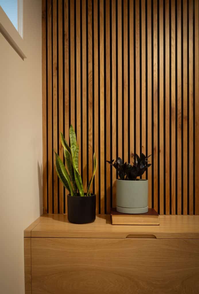 Plants in pots on a wooden cabinet with vertical slat wall, showcasing modern basement design elements by ReCraft Home Remodeling in Portland.