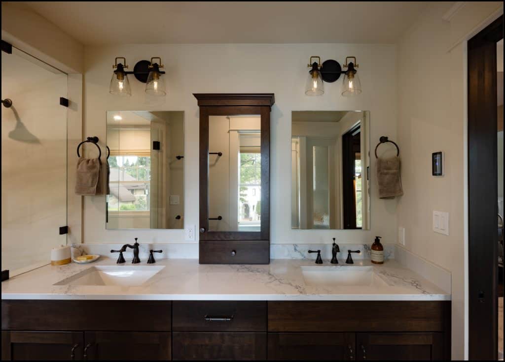 Modern bathroom with double sinks, marble countertop, dark wood cabinets, two mirrors, central cabinet, wall sconces, and towel rings on both sides—an award-winning remodel for a truly stylish space.